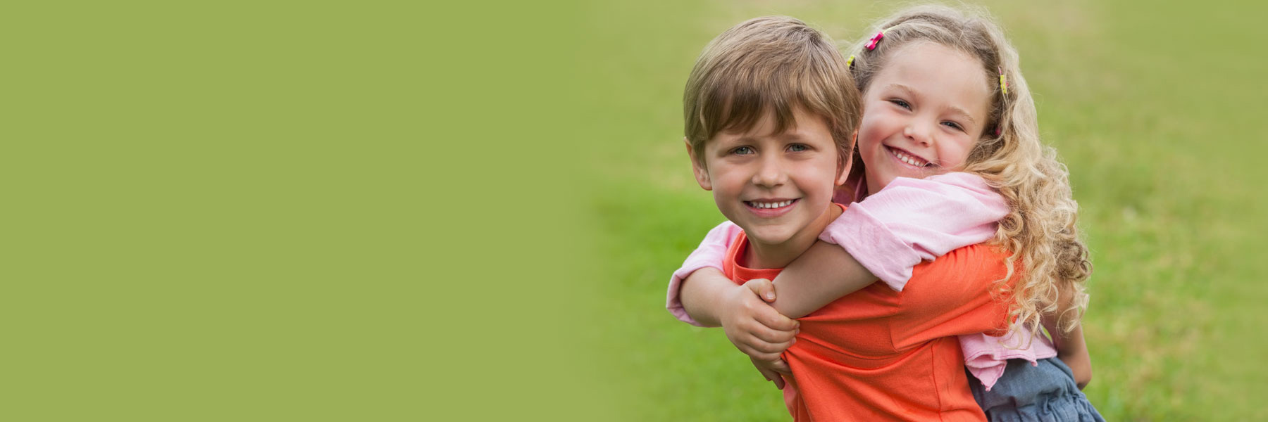 Two happy children hugging and smiling outdoors, showing healthy teeth for kids dentistry guide