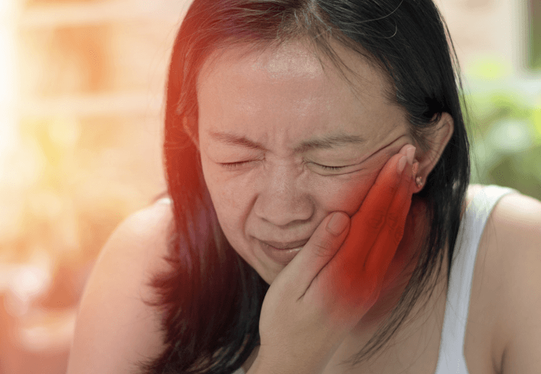 A female patient holding her jaws with a toothache at Sparkling Dental