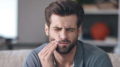 Man holding his jaw due to toothache in Neutral Bay, NSW