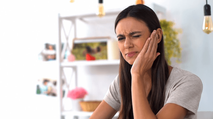 Lady holding her jaw due to pain caused by a cracked tooth in Neutral Bay, NSW