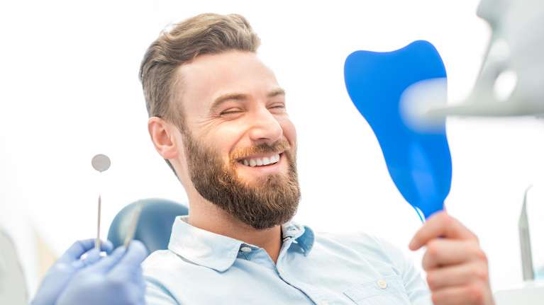 Man looking at himself in the mirror after getting dental fillings in Neutral Bay, NSW