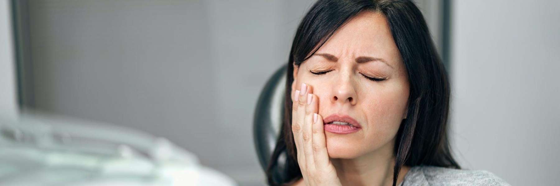 Lady holding her jaw in pain due to toothache in Neutral Bay, NSW